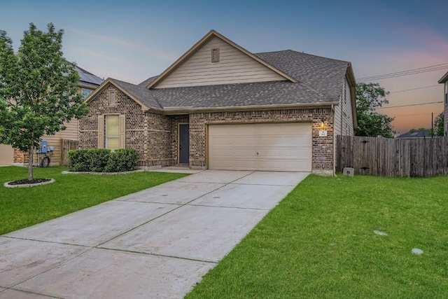 view of front facade featuring roof with shingles, a garage, brick siding, fence, and a yard