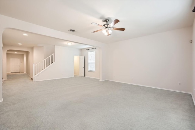 unfurnished room featuring arched walkways, stairs, a ceiling fan, baseboards, and visible vents