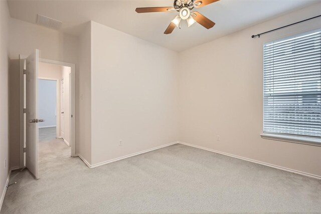 unfurnished room with baseboards, a ceiling fan, visible vents, and light carpet