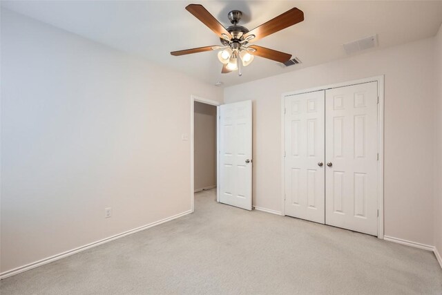 unfurnished bedroom featuring baseboards, light colored carpet, visible vents, and a closet