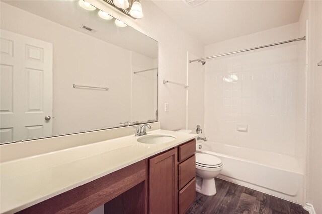 bathroom with vanity, toilet, tub / shower combination, wood finished floors, and visible vents