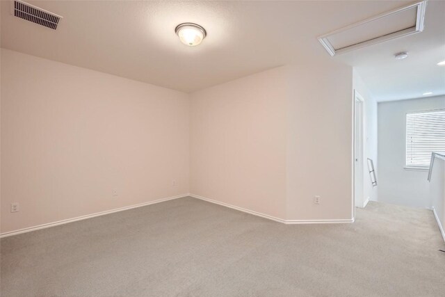 empty room with baseboards, carpet, attic access, and visible vents