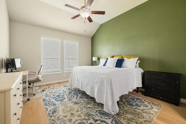 bedroom with ceiling fan, baseboards, vaulted ceiling, and light wood-style flooring