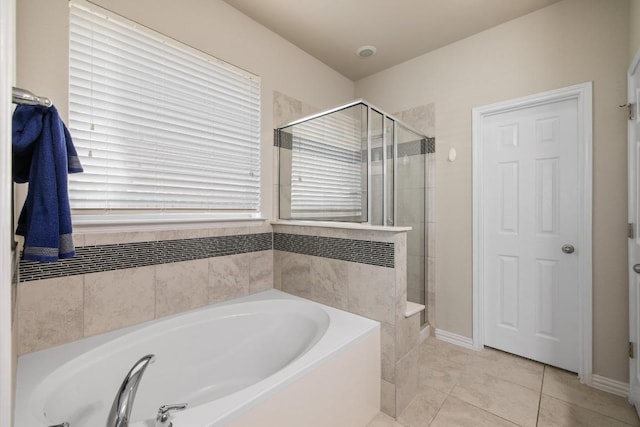 bathroom with tile patterned flooring, a bath, baseboards, and a stall shower