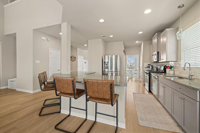 kitchen with a sink, a kitchen island, stainless steel appliances, and a wealth of natural light