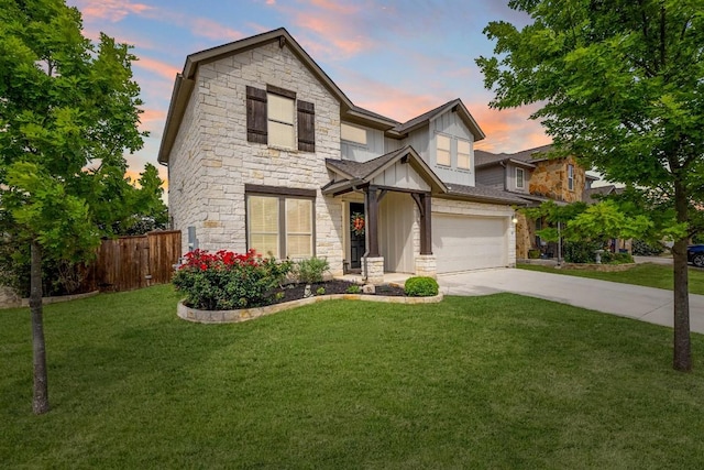 traditional home with fence, stone siding, a garage, a yard, and driveway