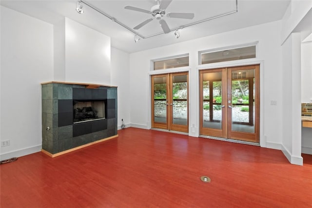 3800 Laurel Ledge Ln, Austin, TX 78731 - unfurnished living room with rail lighting, french doors, wood finished floors, a ceiling fan, and a tiled fireplace