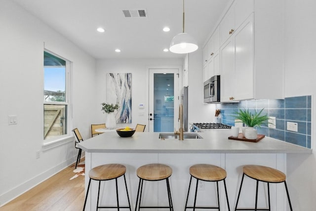 kitchen featuring visible vents, a peninsula, recessed lighting, white cabinets, and stainless steel appliances