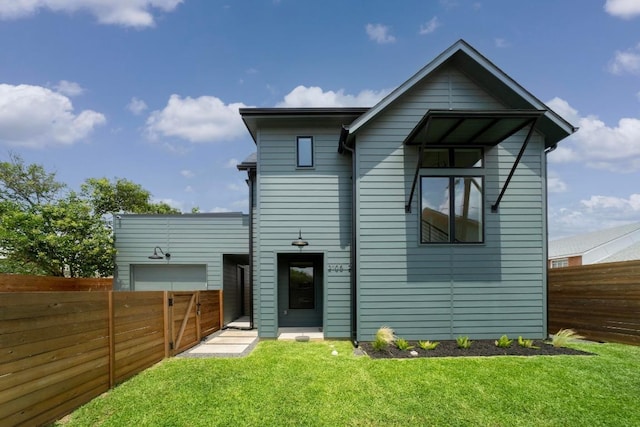 rear view of property with an attached garage, a fenced backyard, and a yard