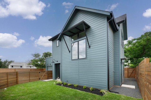 back of property with a fenced backyard, a gate, and a yard