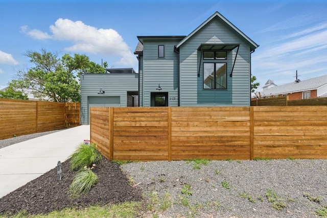 rear view of house with fence private yard, an attached garage, and concrete driveway