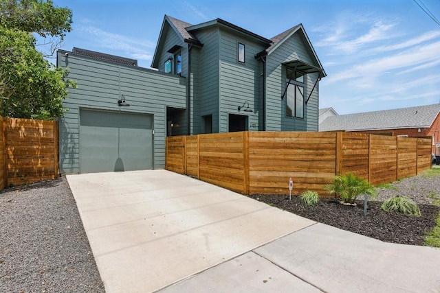 view of side of home with fence private yard, an attached garage, and concrete driveway