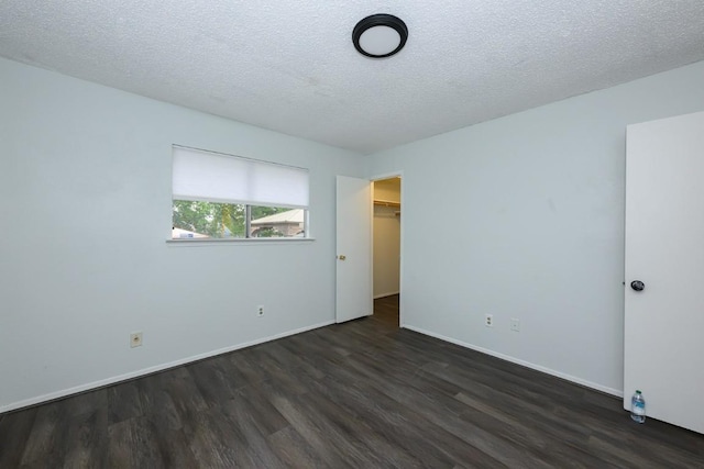 7103 Howerington Cir, Austin, TX 78724 - unfurnished bedroom with dark wood finished floors, baseboards, a textured ceiling, a spacious closet, and a closet