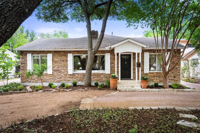 ranch-style house with a shingled roof and stone siding