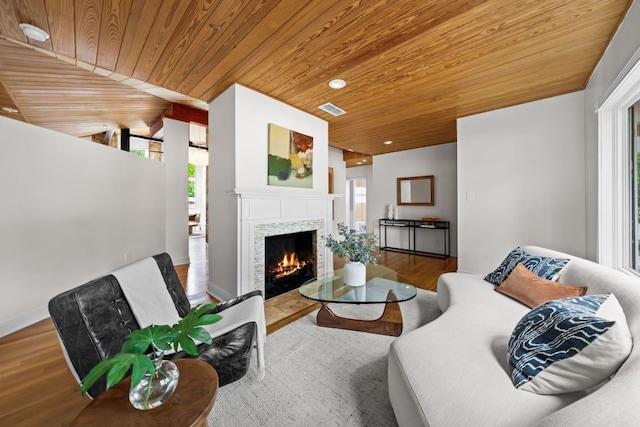 living area with visible vents, a wealth of natural light, and wooden ceiling