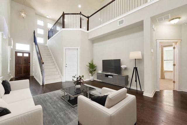living room featuring stairs, visible vents, wood finished floors, and a towering ceiling