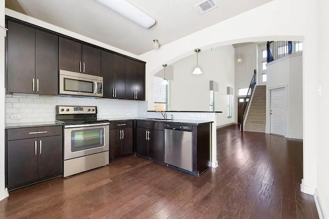 kitchen featuring visible vents, a peninsula, plenty of natural light, arched walkways, and appliances with stainless steel finishes