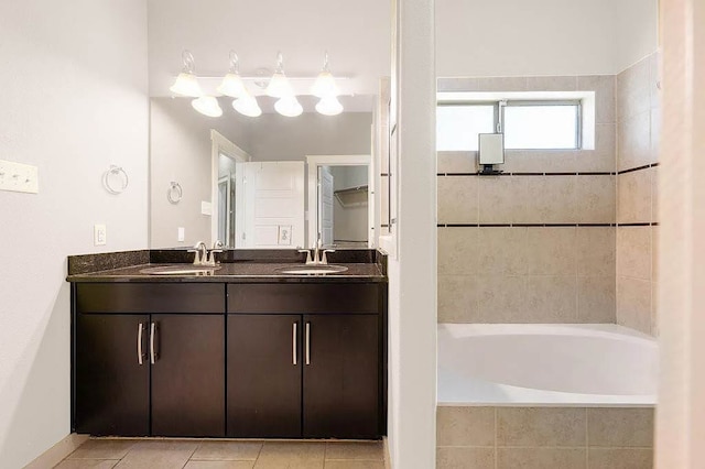 full bath with double vanity, tiled bath, tile patterned floors, and a sink