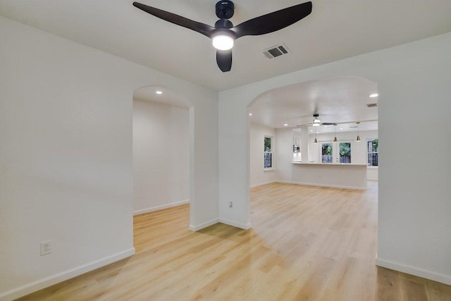unfurnished room with ceiling fan, visible vents, arched walkways, recessed lighting, and light wood-style flooring