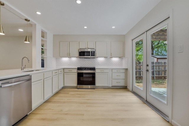 kitchen with a sink, appliances with stainless steel finishes, french doors, and tasteful backsplash