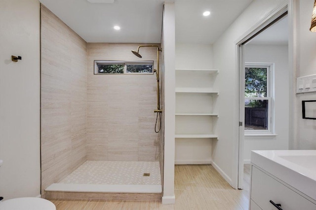 bathroom with recessed lighting, vanity, toilet, and tiled shower