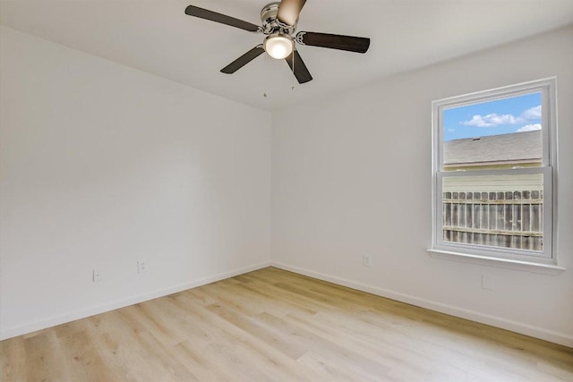 spare room featuring baseboards, light wood finished floors, and ceiling fan