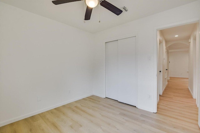 unfurnished bedroom with visible vents, a closet, baseboards, a ceiling fan, and light wood-style flooring