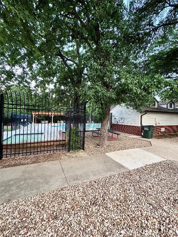view of gate featuring fence and a community pool