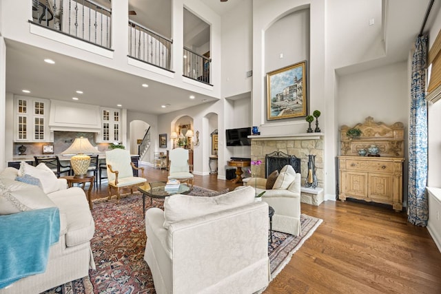 103 Maddy Way, Austin, TX 78738 - living room with arched walkways, a fireplace, wood finished floors, a high ceiling, and recessed lighting