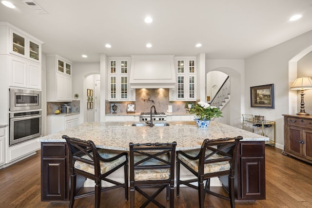 103 Maddy Way, Austin, TX 78738 - kitchen featuring stainless steel appliances, premium range hood, arched walkways, backsplash, and recessed lighting