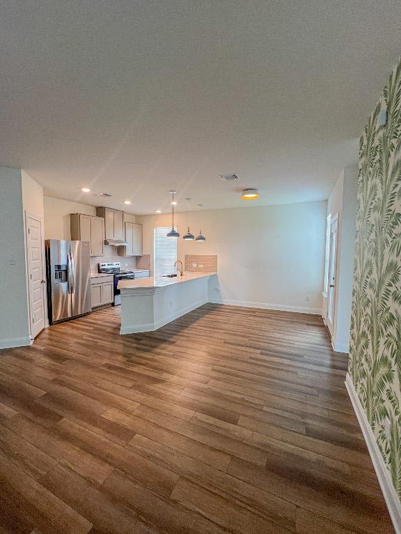 kitchen featuring dark wood finished floors, light countertops, a sink, a peninsula, and stainless steel appliances