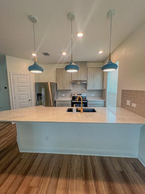 kitchen featuring visible vents, appliances with stainless steel finishes, tasteful backsplash, a sink, and dark wood-style floors