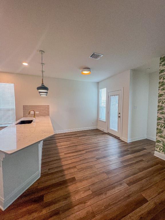 interior space with a sink, baseboards, dark wood-style flooring, and visible vents