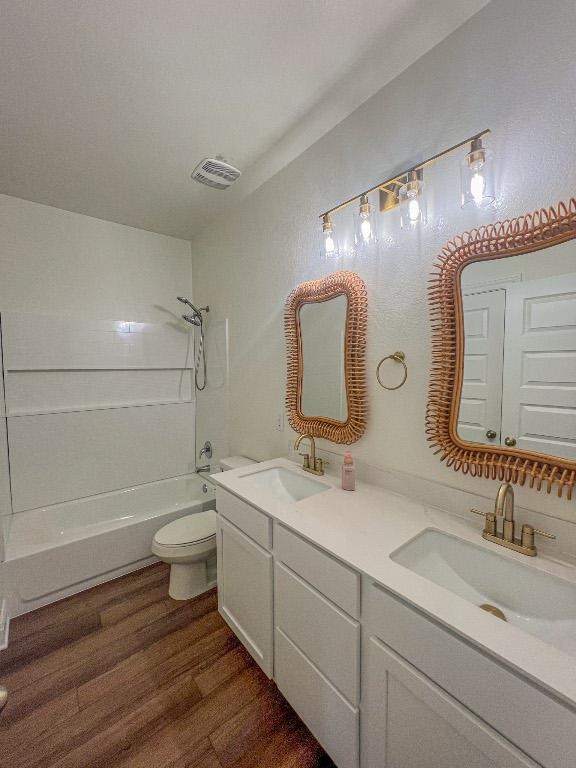 bathroom with a sink, bathtub / shower combination, toilet, and wood finished floors