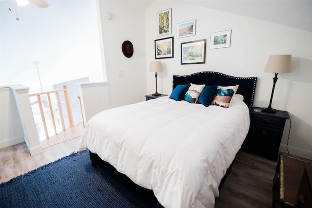 bedroom with baseboards, wood finished floors, and lofted ceiling