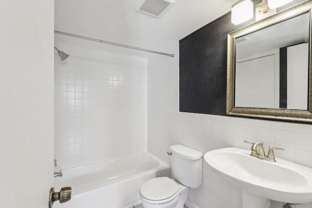 bathroom with toilet, visible vents, bathing tub / shower combination, and a sink