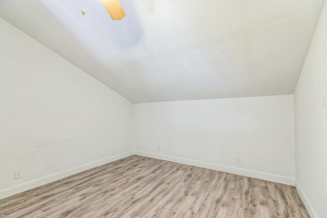 bonus room with baseboards, light wood-style flooring, ceiling fan, and vaulted ceiling