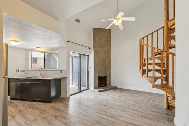 unfurnished living room featuring visible vents, a sink, high vaulted ceiling, light wood finished floors, and stairs