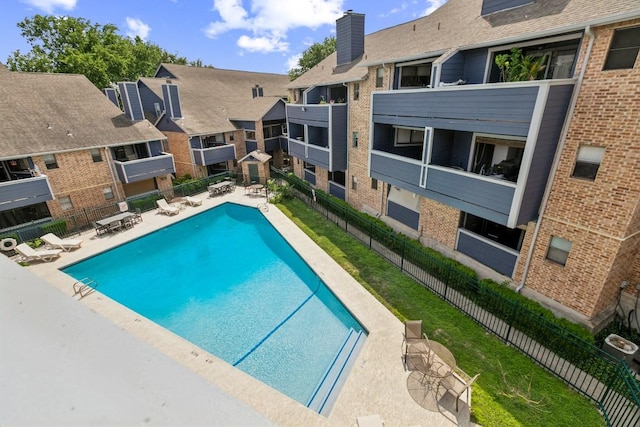 pool with a patio, fence, and a residential view