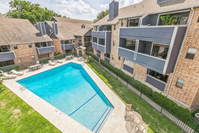 community pool with a patio, fence, and a residential view