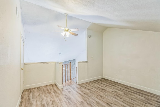 bonus room featuring ceiling fan, a textured ceiling, baseboards, wood finished floors, and lofted ceiling