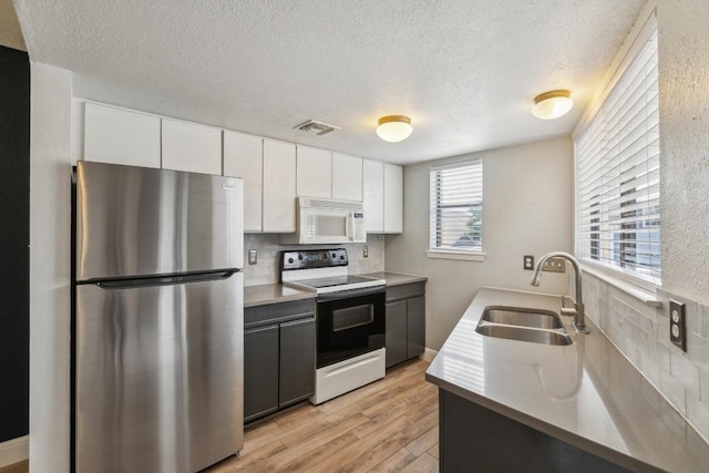 2500 Burleson Rd Unit 321, Austin, TX 78741 - kitchen featuring a sink, electric range oven, a textured ceiling, freestanding refrigerator, and white microwave