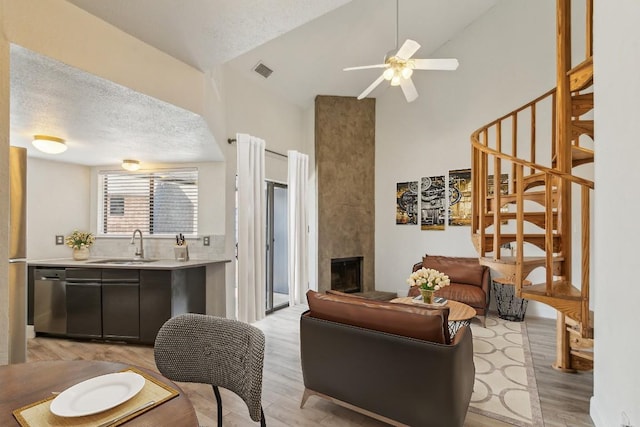 2500 Burleson Rd Unit 321, Austin, TX 78741 - living area featuring visible vents, a fireplace, ceiling fan, stairway, and light wood-type flooring