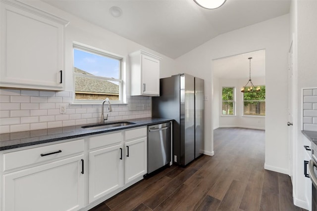 kitchen featuring appliances with stainless steel finishes, a sink, dark wood finished floors, decorative backsplash, and lofted ceiling