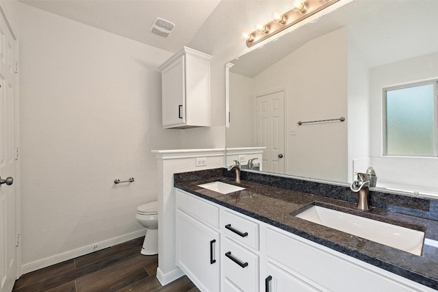 bathroom with baseboards, visible vents, a sink, and wood finished floors