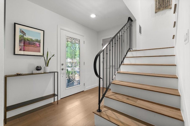 foyer entrance with recessed lighting, baseboards, wood finished floors, visible vents, and stairway