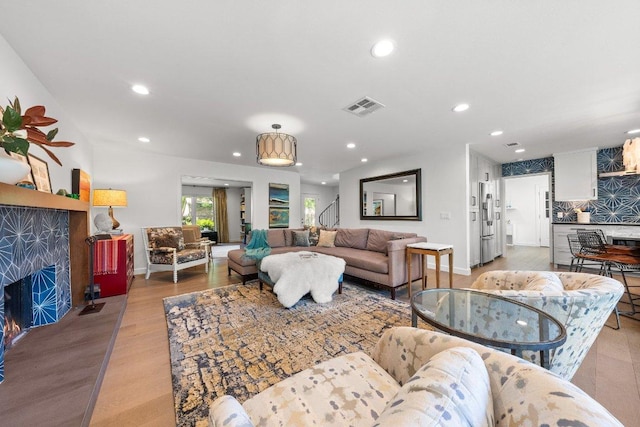 living area with visible vents, a fireplace, baseboards, recessed lighting, and light wood-style flooring