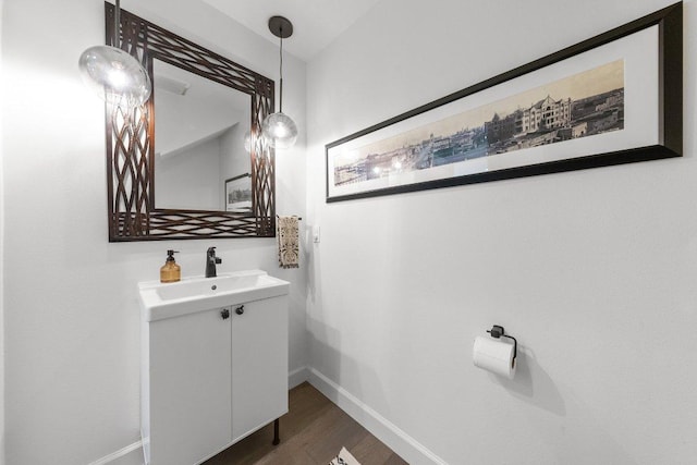bathroom with baseboards, wood finished floors, and vanity