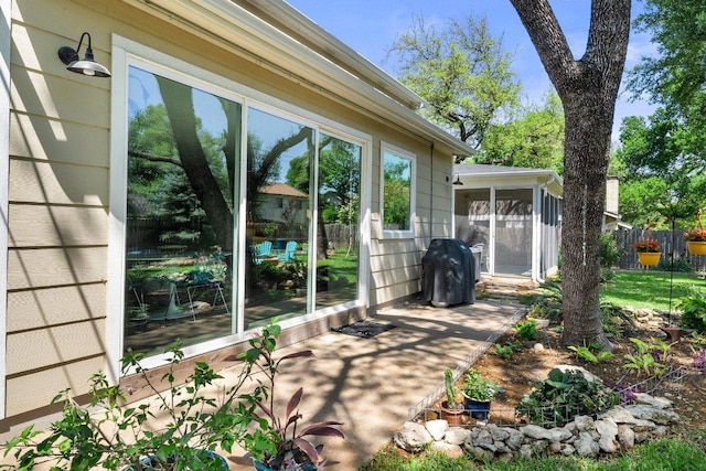 view of patio featuring fence and a sunroom