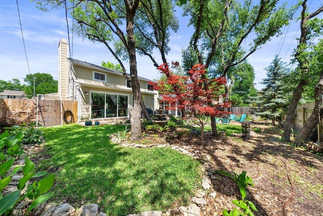 exterior space featuring a fenced backyard, a chimney, and a yard